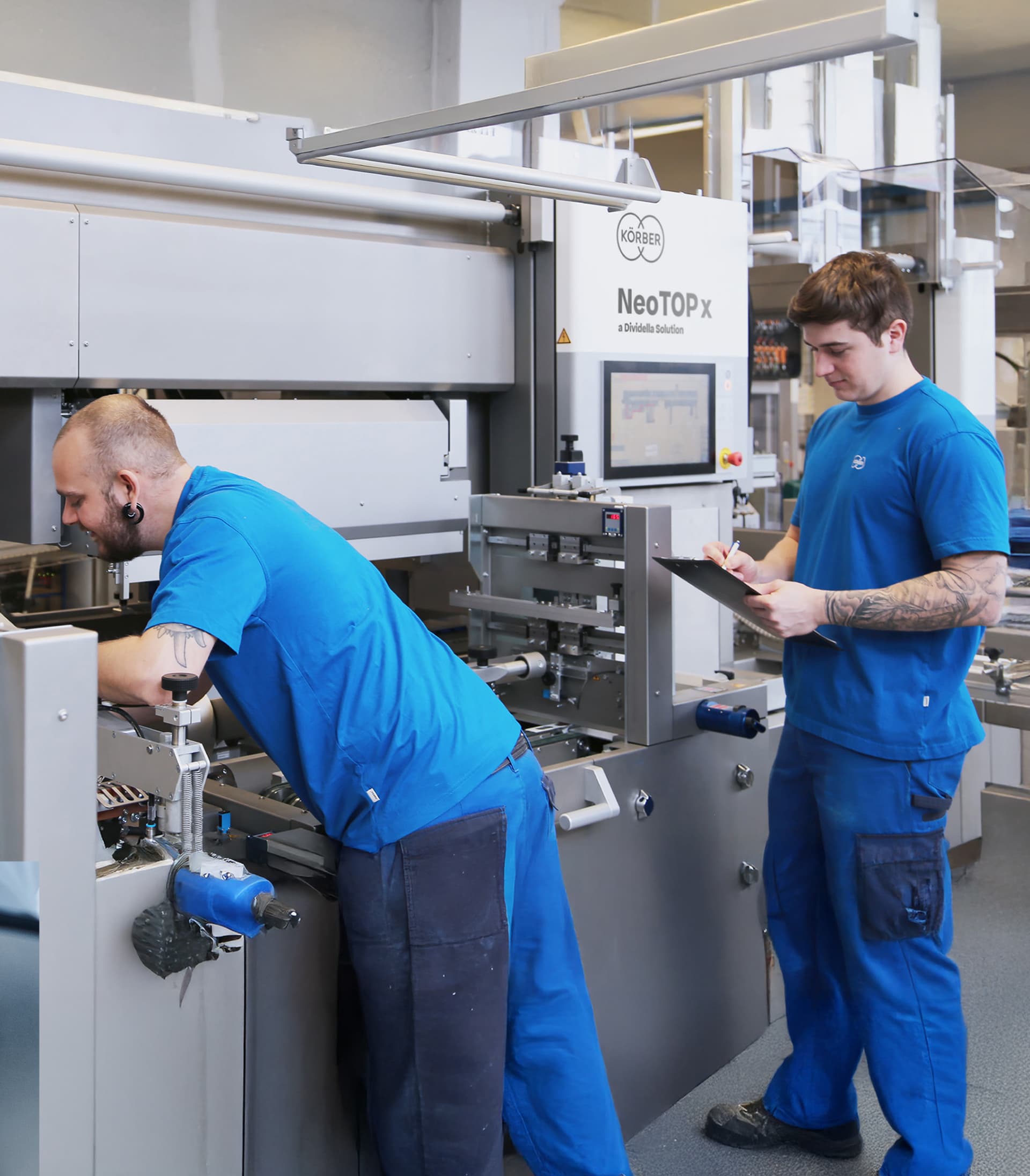 Two Körber employees servicing machinery