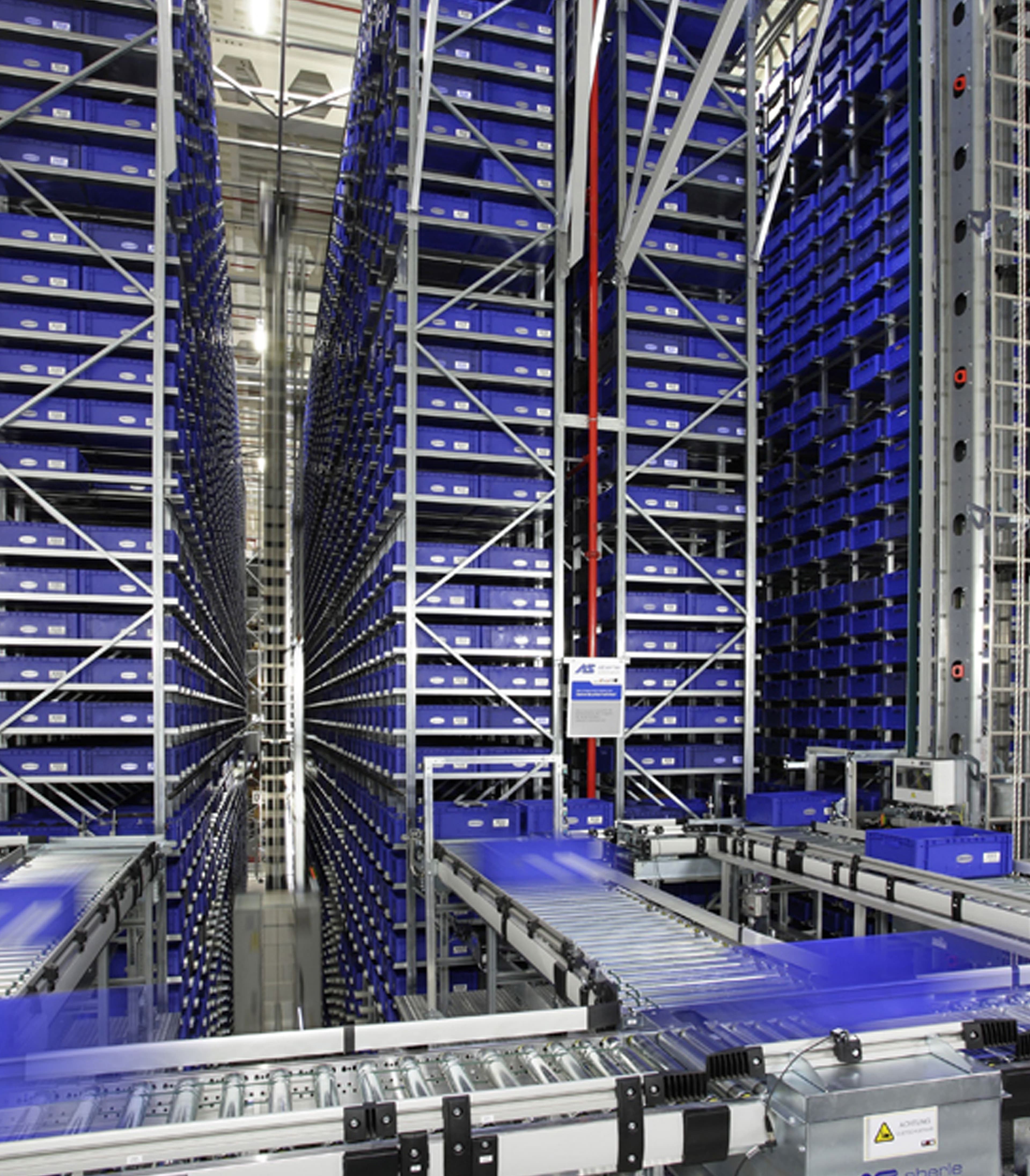 Körber automated warehouse with high racks and conveyor system for blue containers.