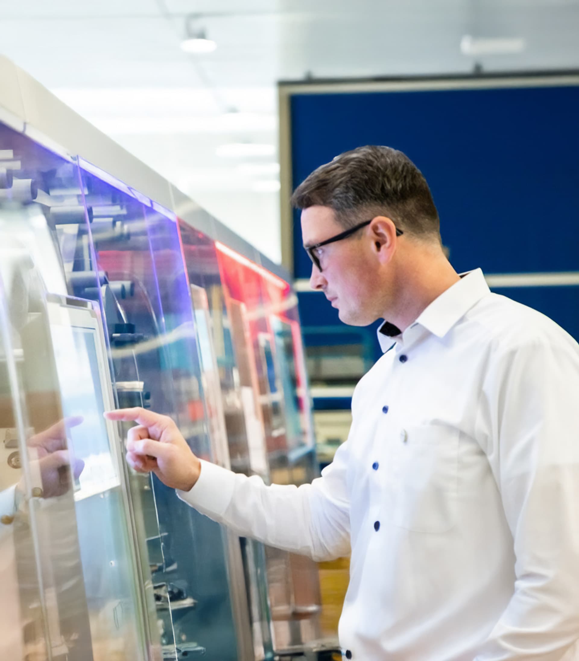 A Koerber employee using a touchscreen interface on an industrial machine.