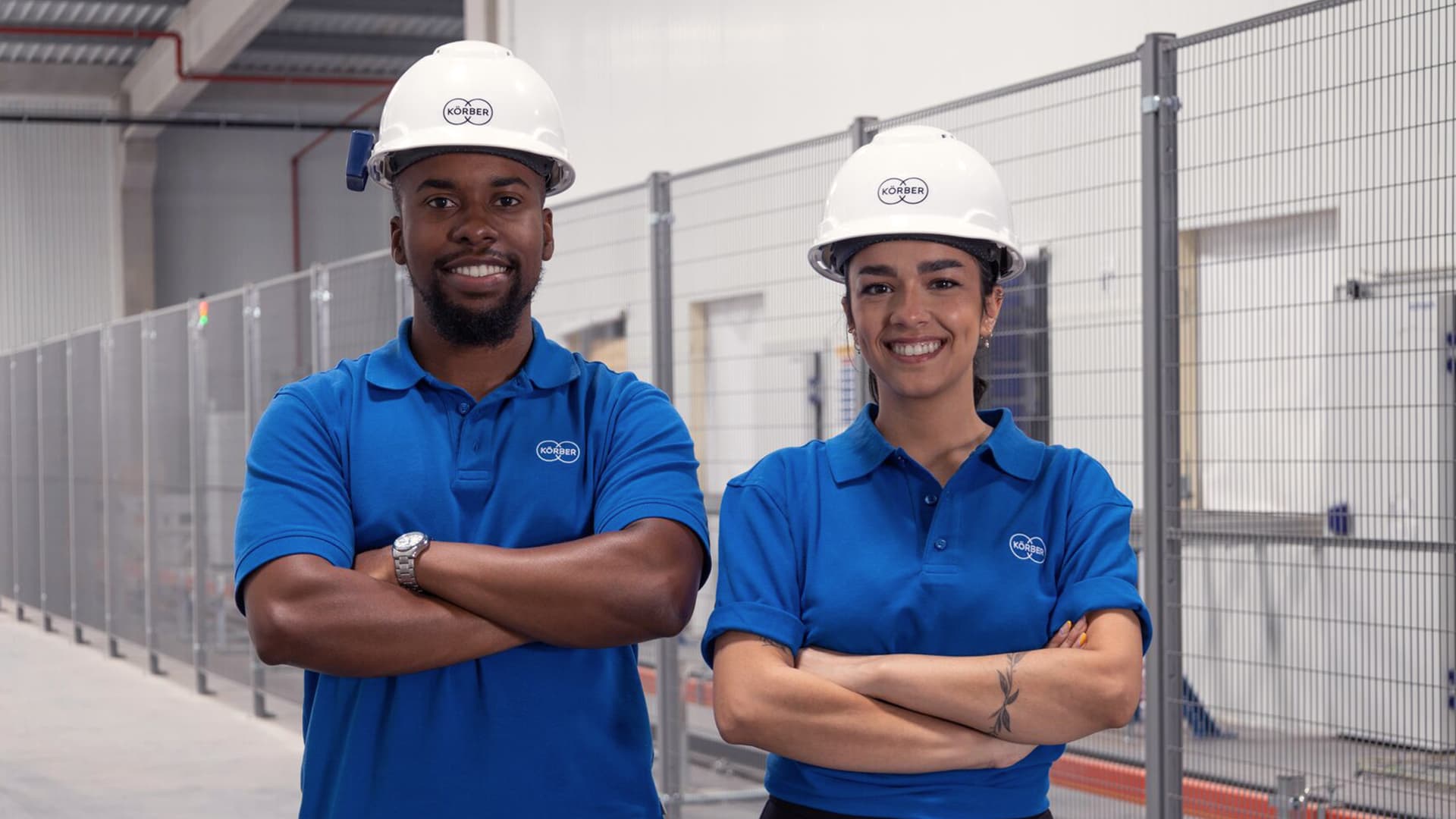 Two Körber employees wearing hard hats smiling