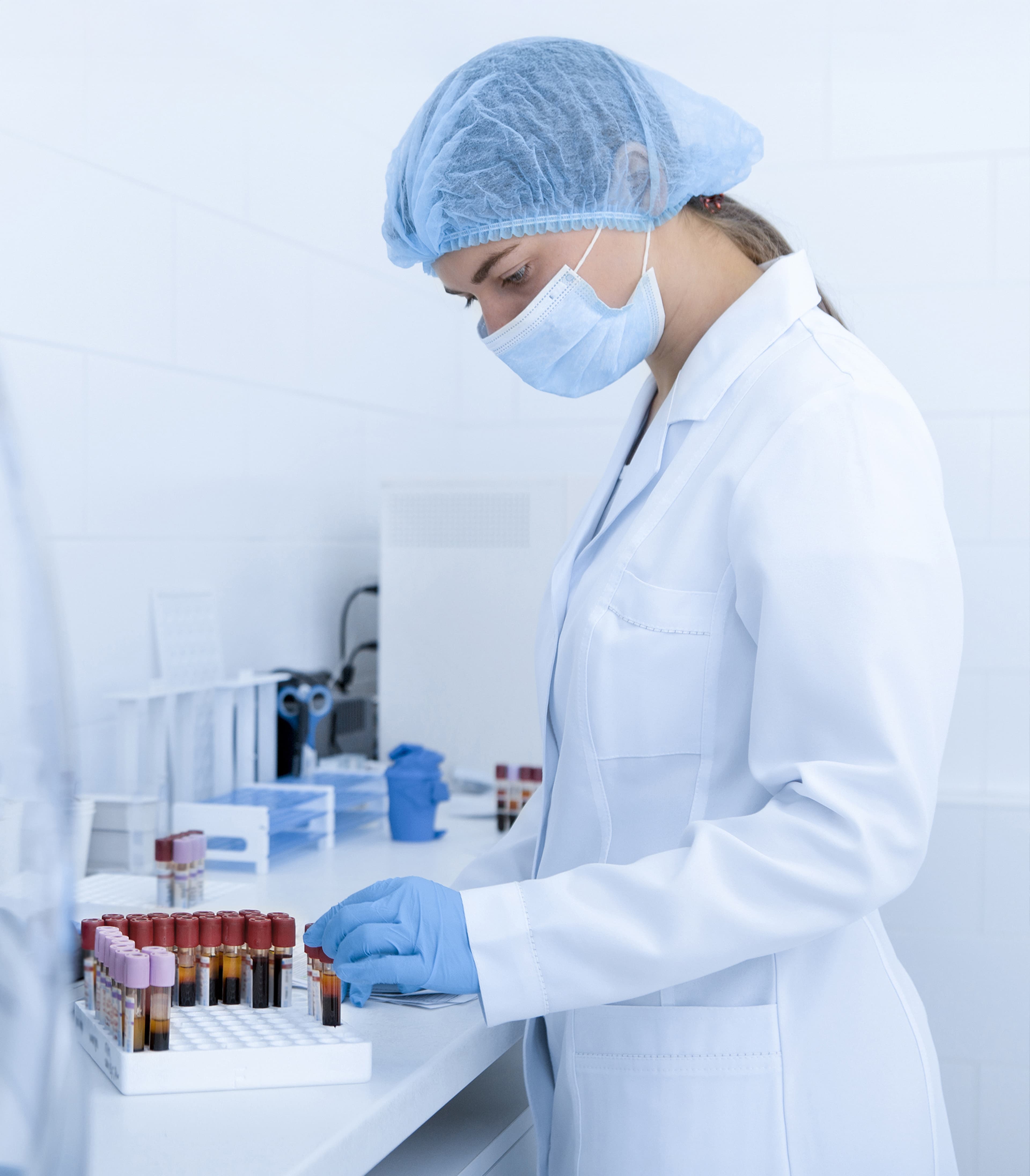 Woman wearing personal protective equipment working with blood samples in a lab