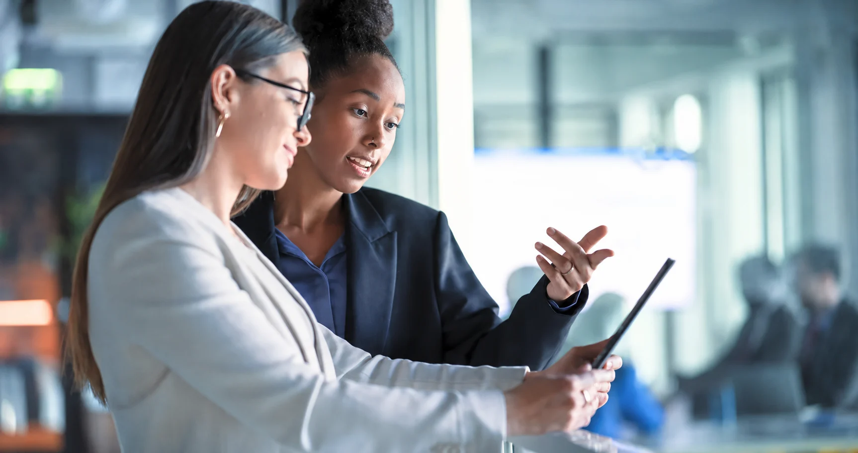Women looking ar a tablet screen and discussing numbers.