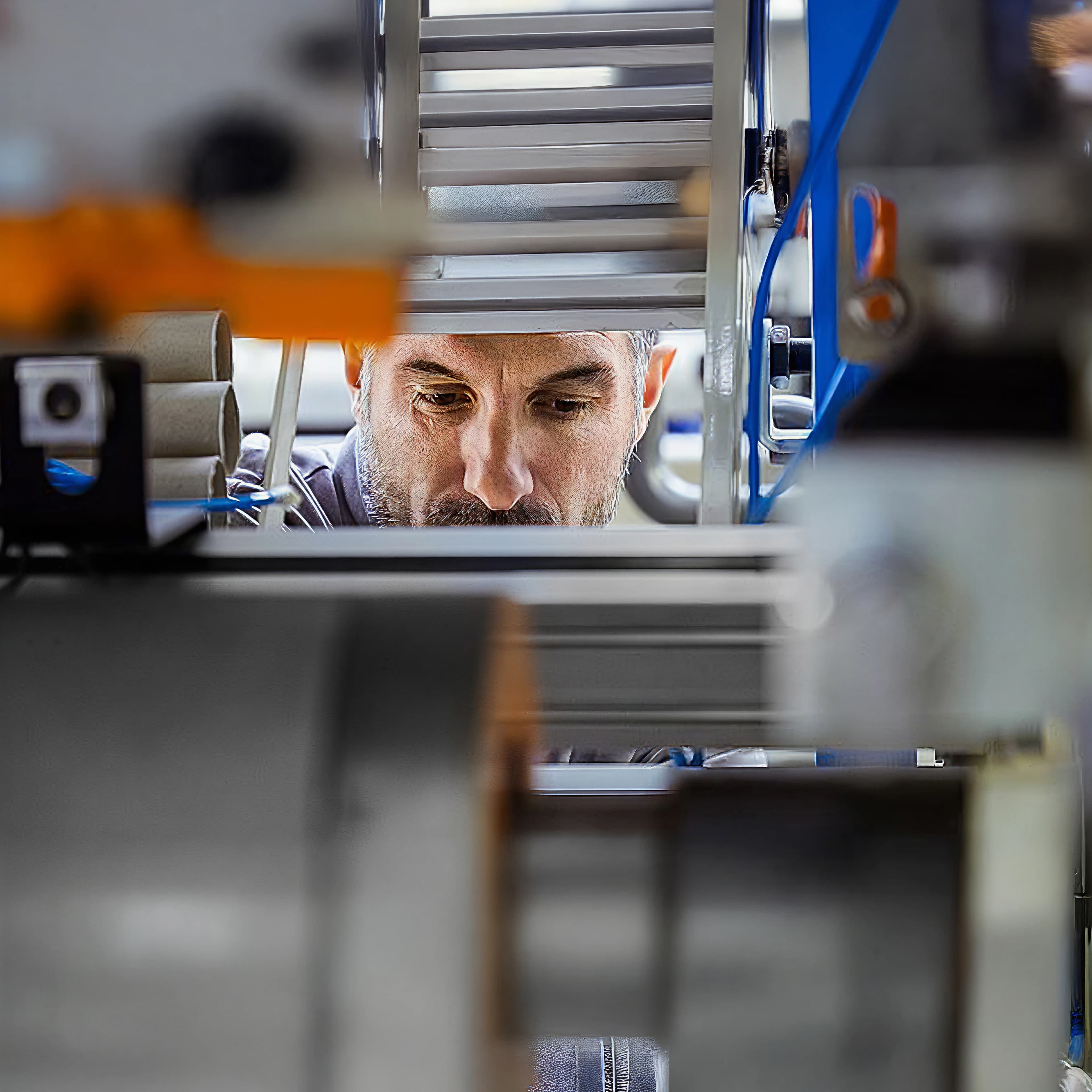 Fotografie eines Mannes, der durch einen Spalt in einer Maschine gesehen wird.