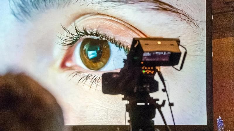 A person watches a large screen showcasing the potential of artificial intelligence, filmed by a nearby camera.