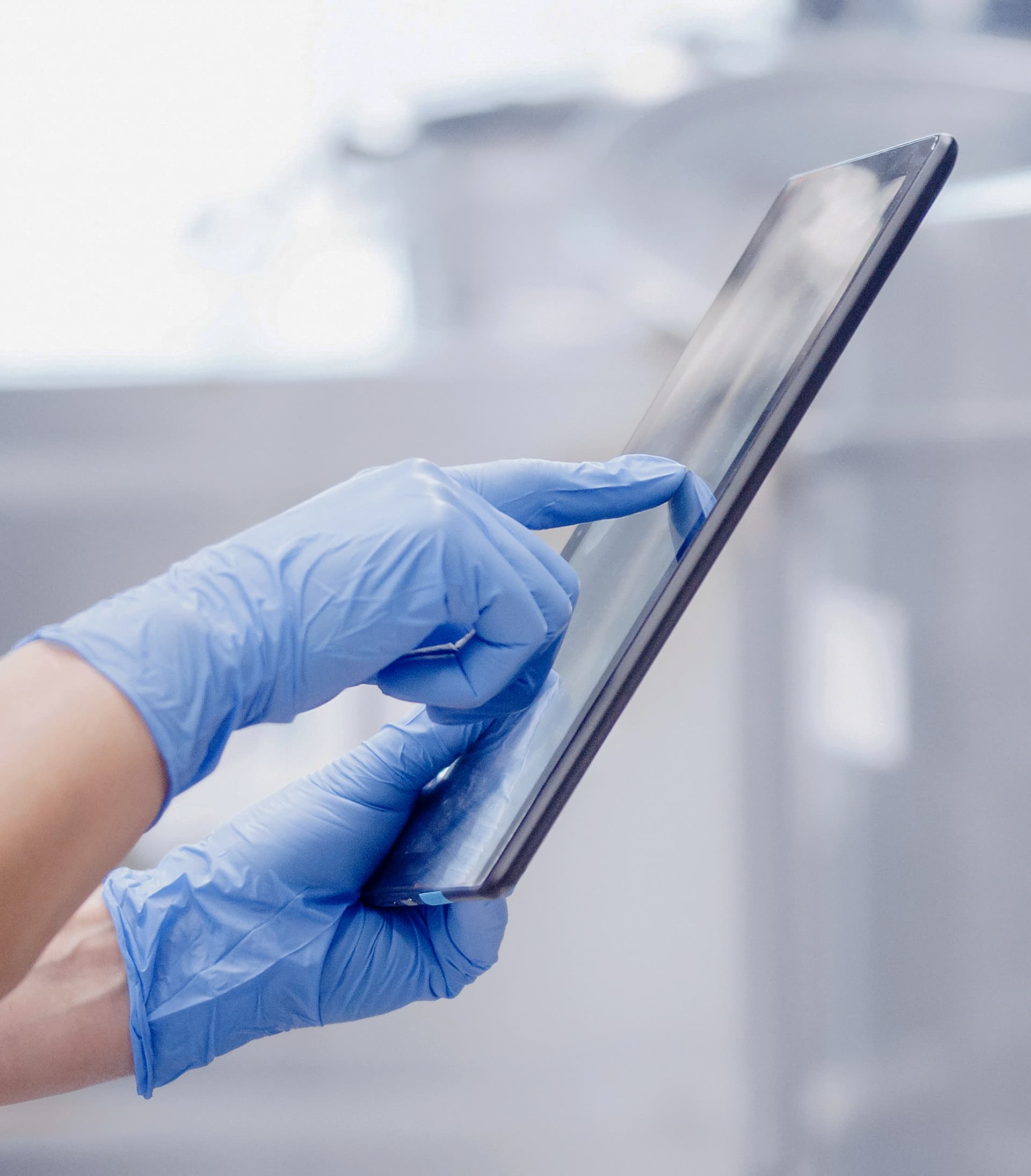 Eine Hand mit einem chirurgischen blauen Handschuh berührt einen Bildschirm.