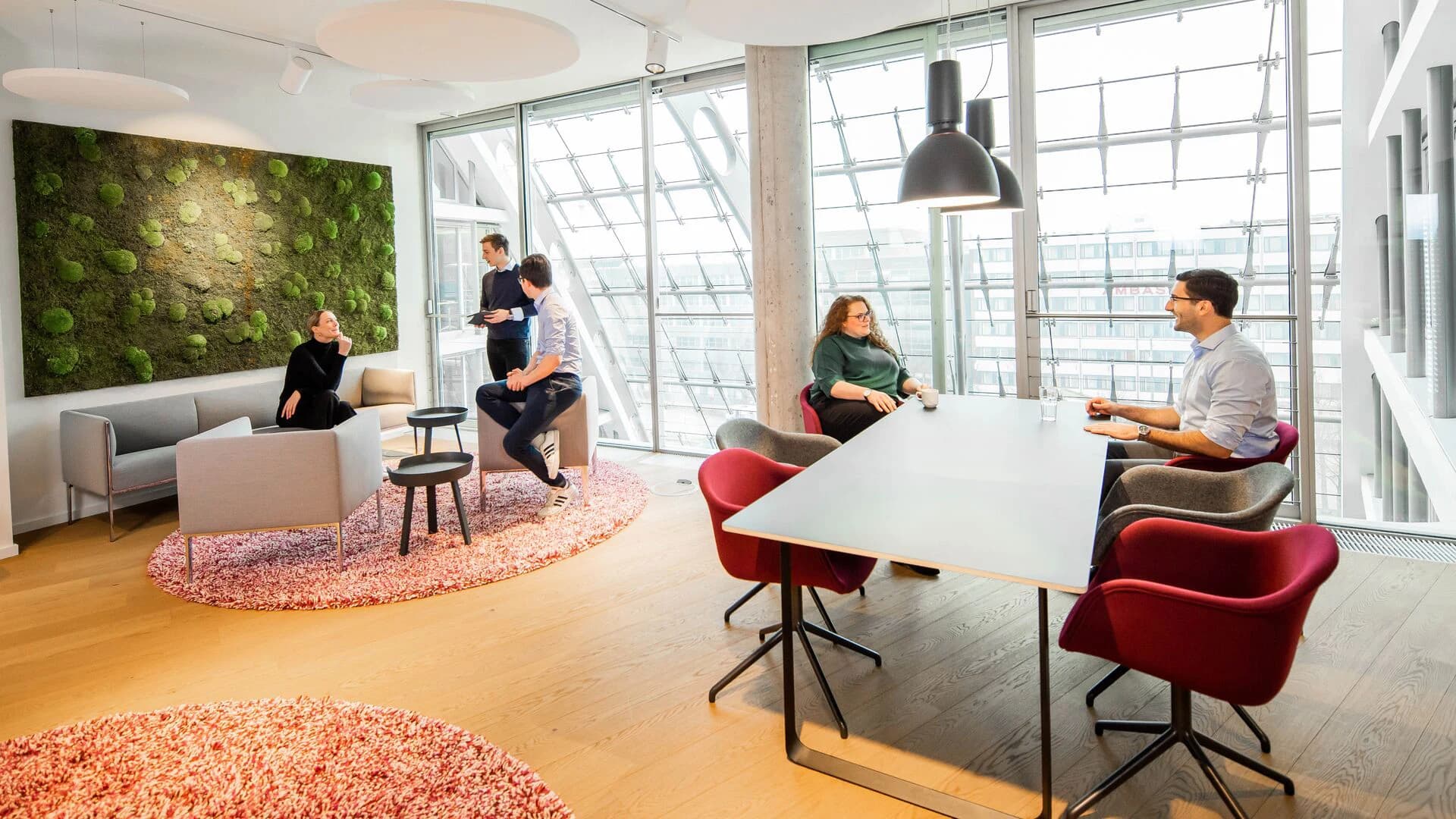 A group of people engaged in discussion while seated around a conference table in an office setting.