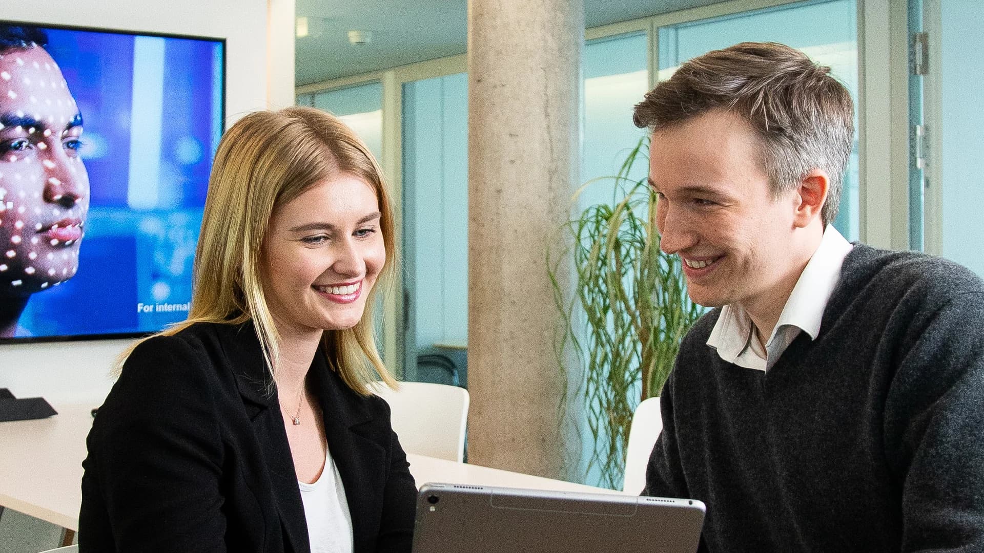 Ein Mann und eine Frau sitzen an einem Tisch und benutzen einen Laptop