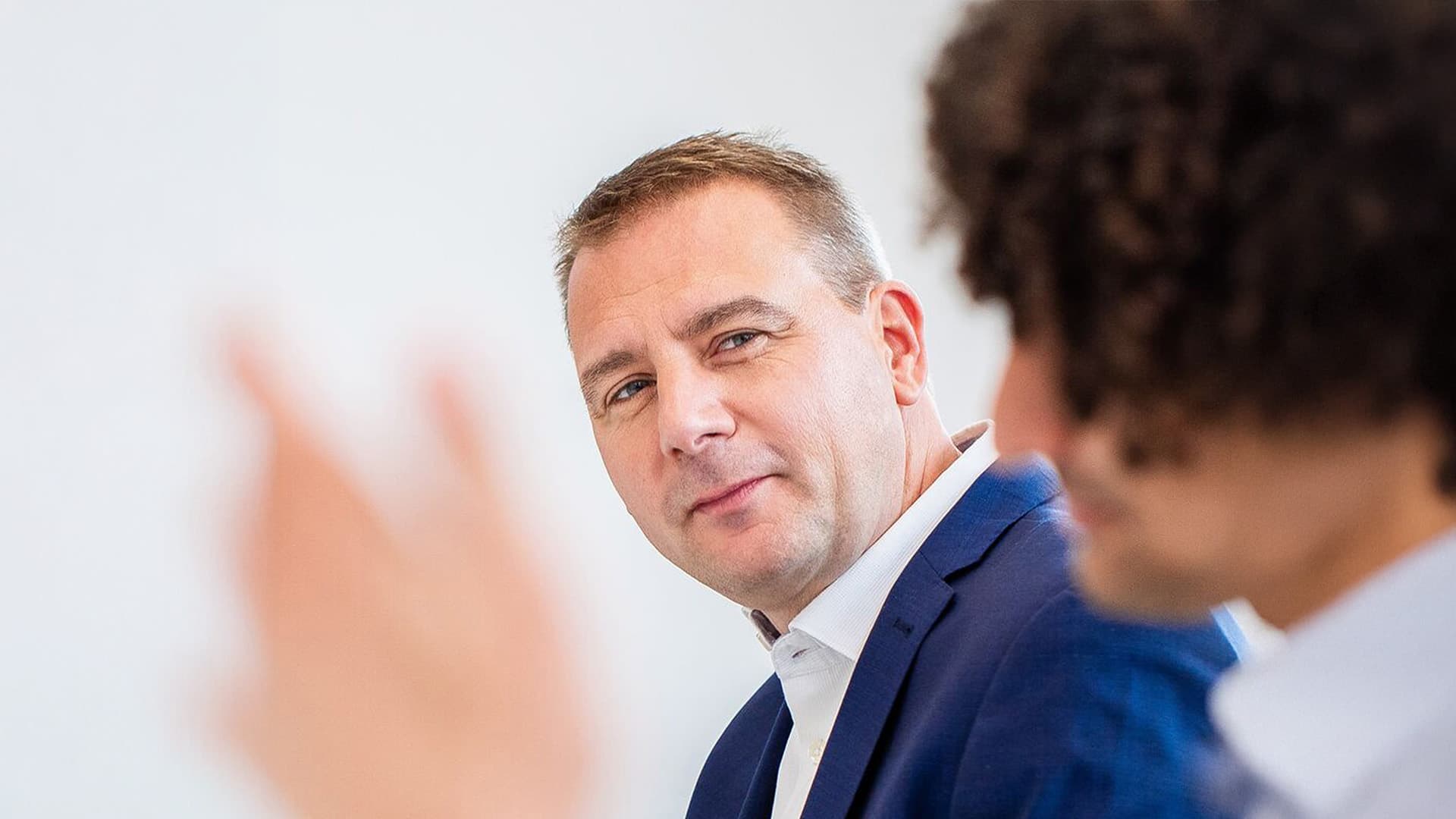 Mann in blauem Anzug, der eine Person außerhalb des Fokus betrachtet