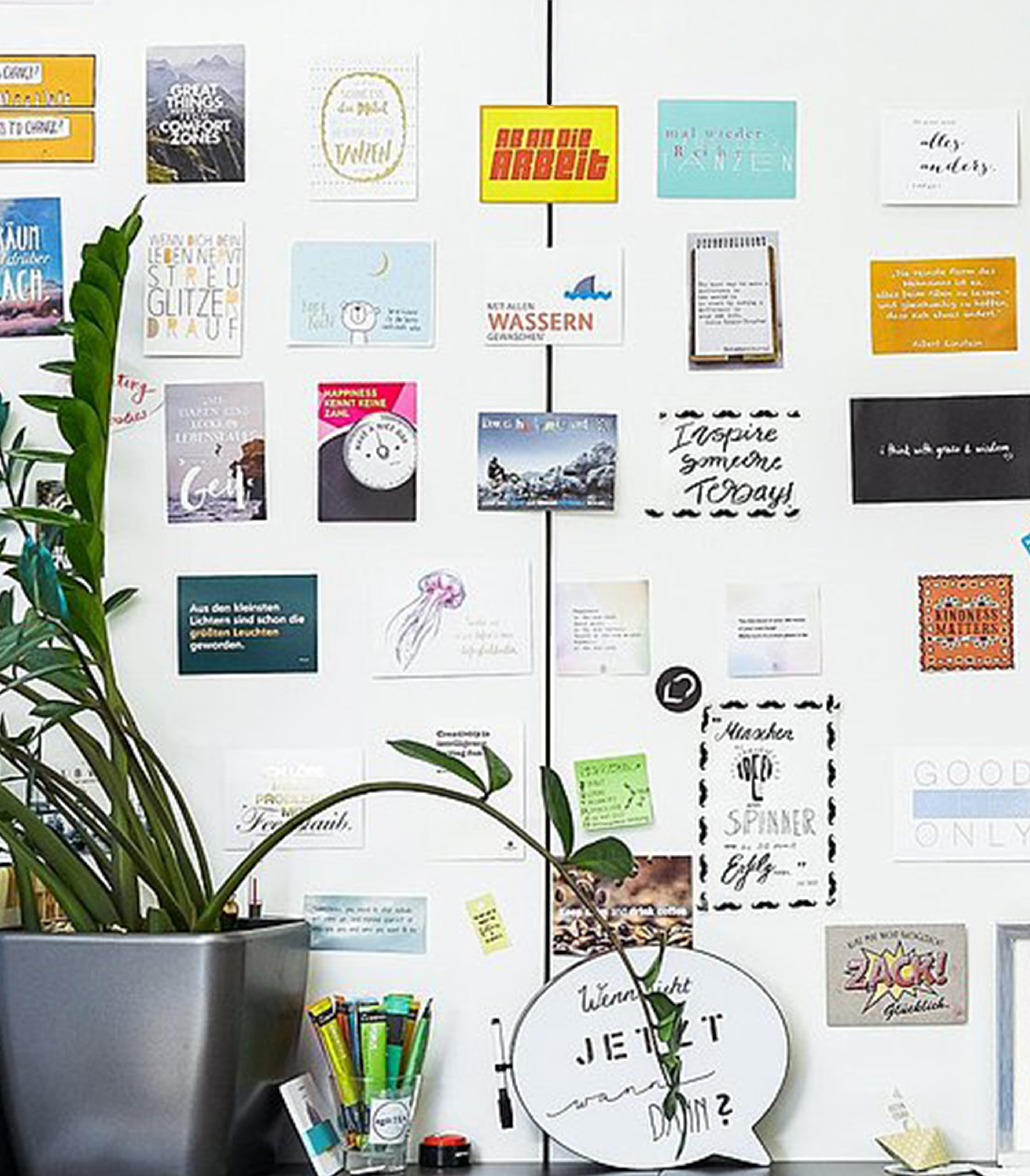 Wand mit Postkarten bedeckt und eine Pflanze auf einem Regal