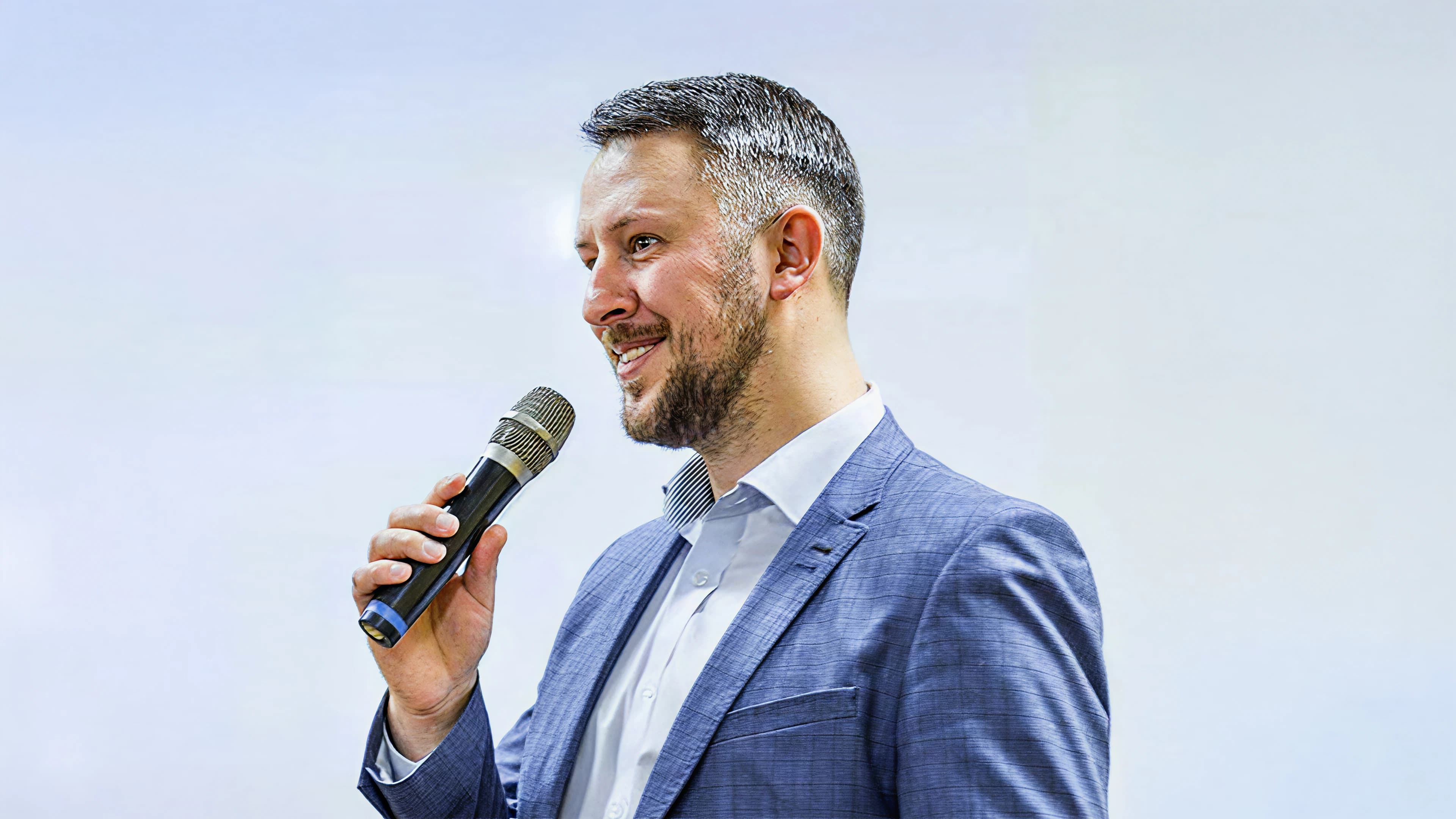 Mann hält ein Mikrofon und präsentiert