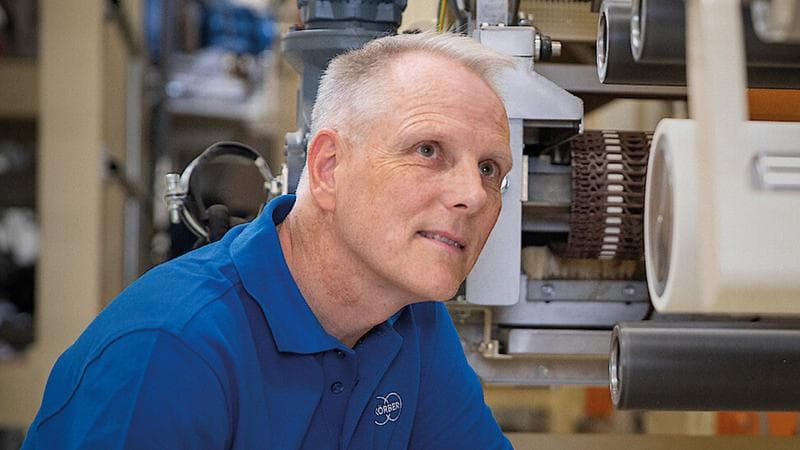 Körber-Mitarbeiter vor Maschinen mit Blick in die Kamera, aber mit Blick nach oben.