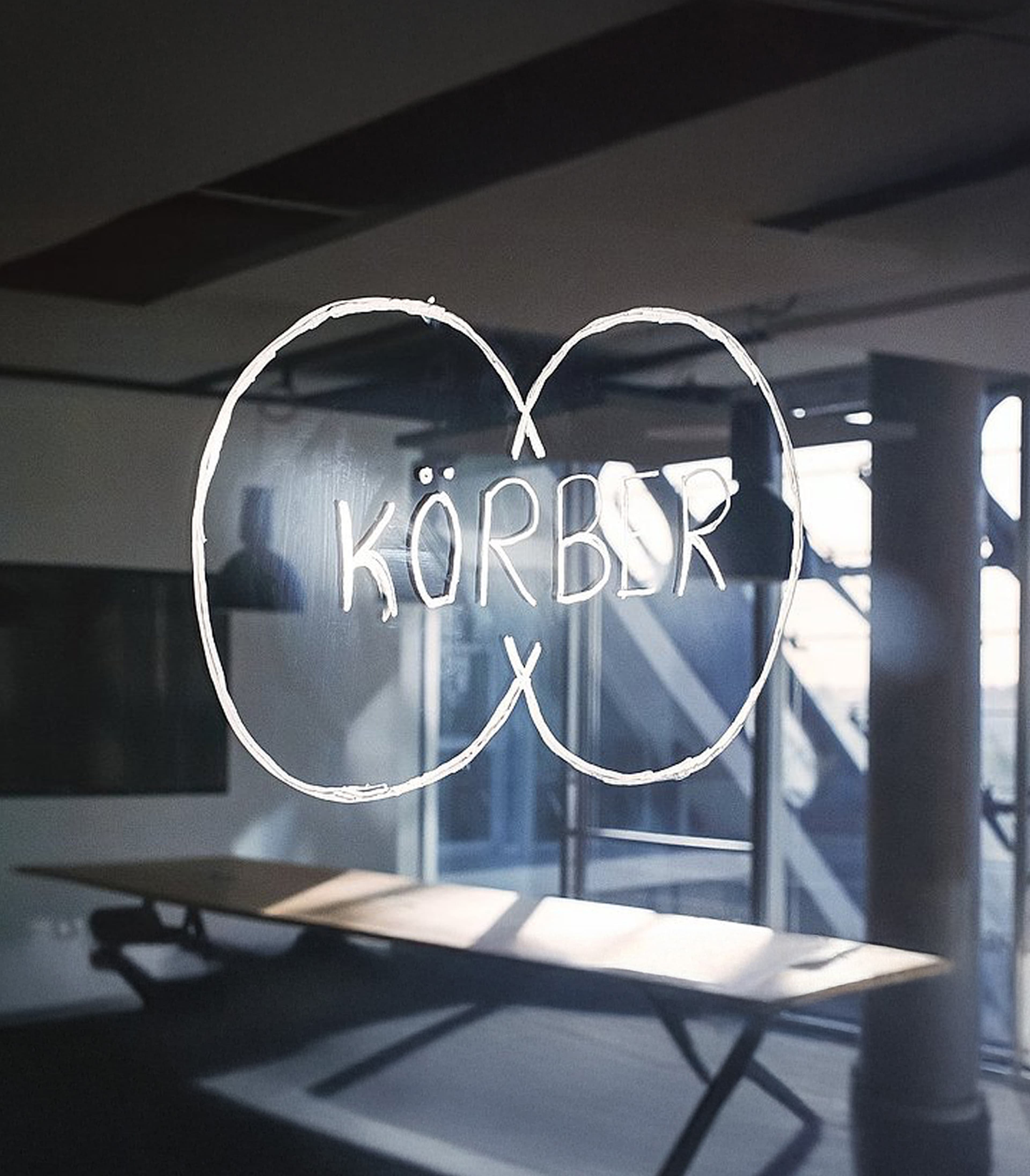 Körber-Logo, mit weißem Stift auf ein Glasfenster gezeichnet